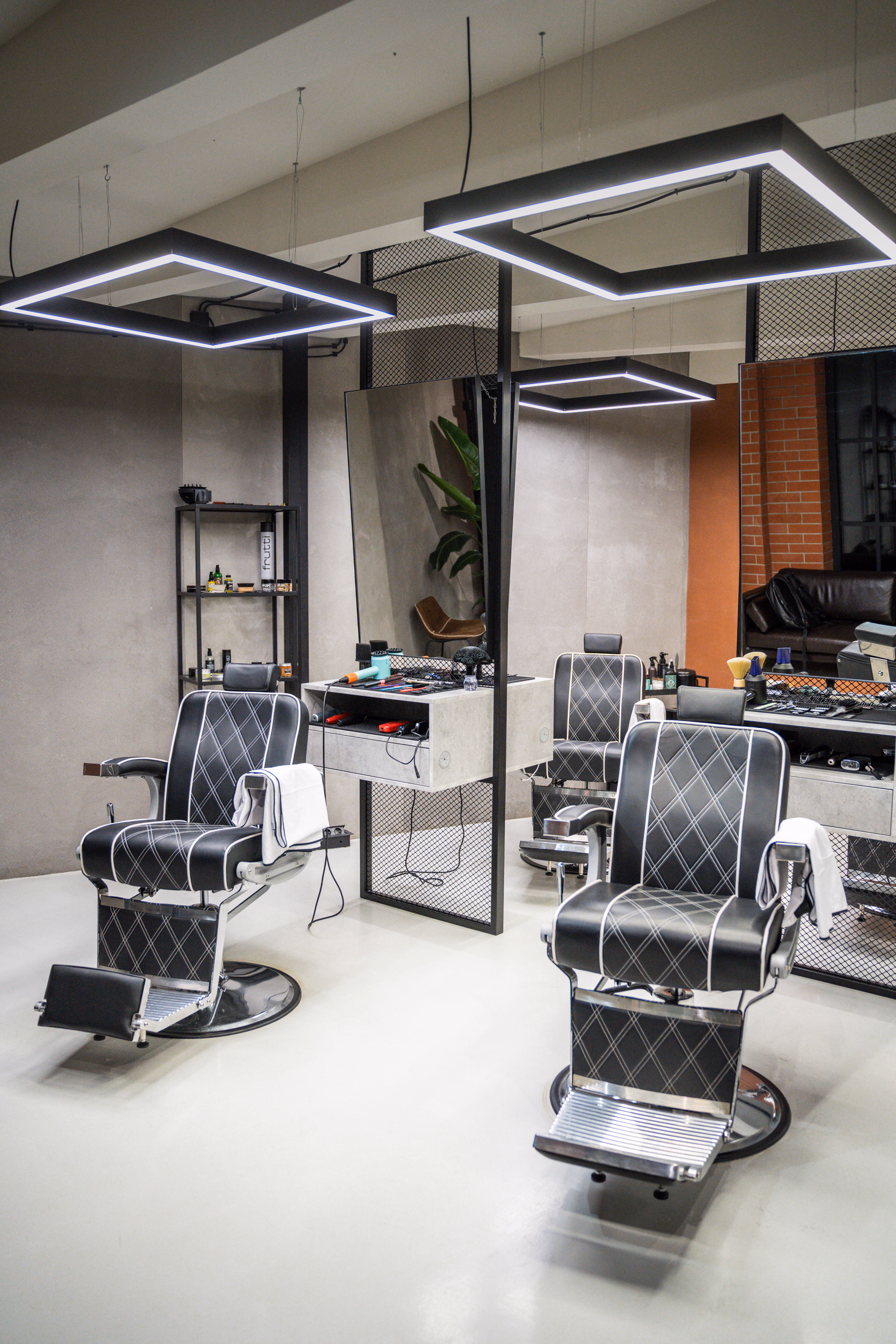 Sala Horizon Barbershop w Krakowie: stanowiska barberskie z fotelami, lustrami i oświetleniem